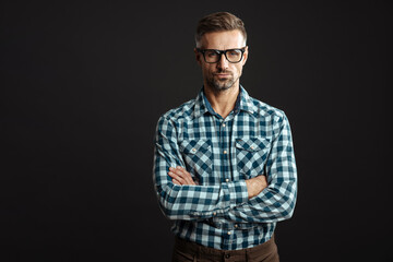 Handsome confident man in eyeglasses posing with arms crossed