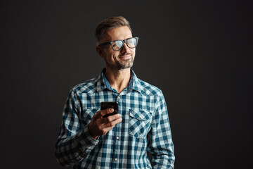 Handsome happy man in eyeglasses using mobile phone