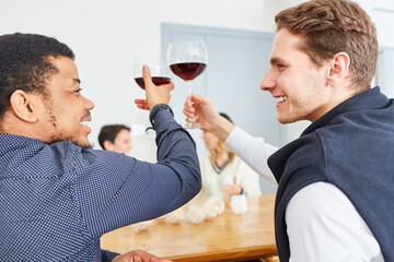 Two men toast with glass of wine at party at home