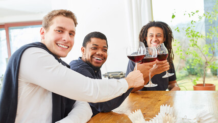 Obraz premium Men as friends toasting with a glass of red wine in a shared kitchen