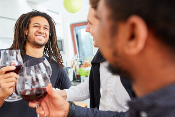 Friends toasting with glass of red wine at party in shared apartment