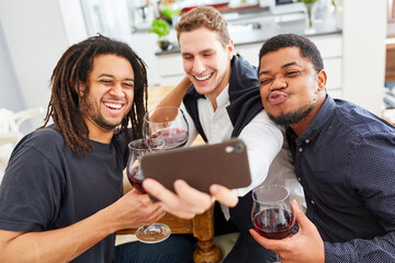 Three men as friends make funny selfie with smartphone