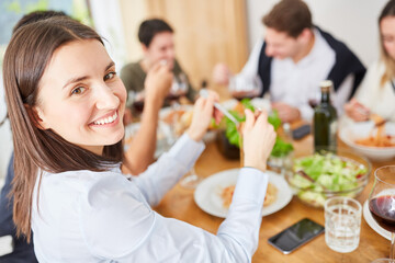 Woman with friends having dinner in the kitchen of a shared apartment