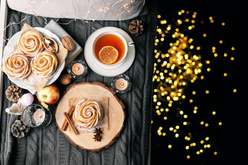 A cup of hot tea with lemon in an early winter morning by the window. Knitted wool warm blanket, hot homemade apple cakes with cinnamon and star anise . Decor. Home winter holiday concept.