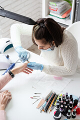 Manicure master using nippers to make manicure to a client