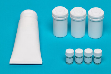 Closeup various white medical or cosmetic jars or containers without labeling on a blue background. Concept of spa applications, cosmetic treatments or other beauty and make-up products.