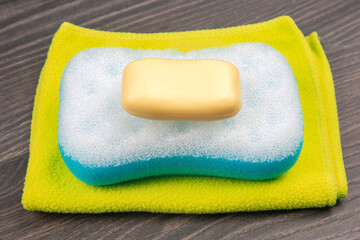 bath sponge, soap and towel on wooden background