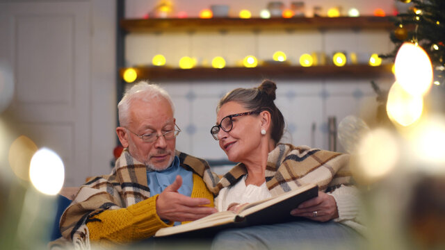 Senior couple reading book during christmas evening - Powered by Adobe