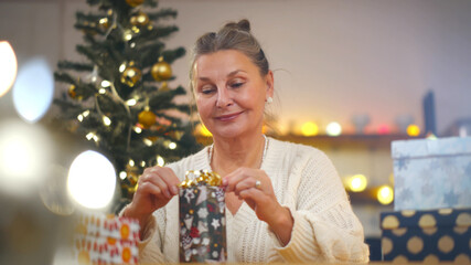 Happy senior woman wrapping christmas presents for grandchildren