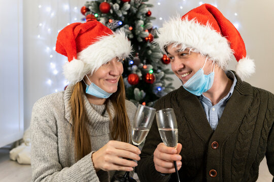 Happy married couple in protective masks drinks champagne for christmas. Family new year during quarantine covid 19 pandemic safe at home