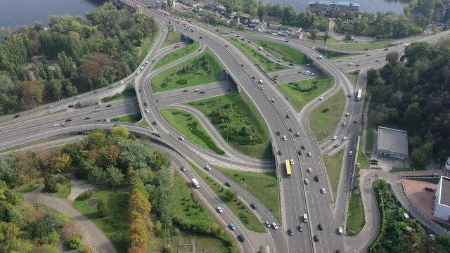 Europe, Kiev, Ukraine - November 2020: Aerial view of the Automobile junction and Paton bridge in the city. Car traffic Potona bridge. Circular movement of cars.