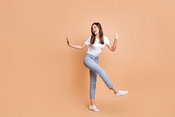 Fototapeta na wymiar Full length body size photo of dancing at party girl smiling looking blank space isolated on pastel beige color background