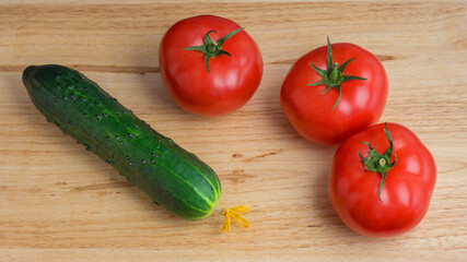 ripe fresh tomato and cucumber on a wooden background