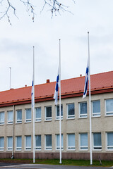 Three finnish flags lowered to half mast on the occasion of mourning at cloudy autumn day