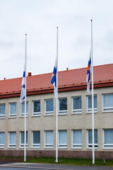 Three finnish flags lowered to half mast on the occasion of mourning at cloudy autumn day