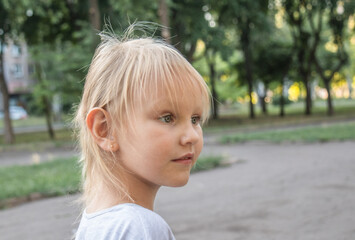 Profile of a little cute girl with white hair, 5 years old, who looks into the distance with surprise.