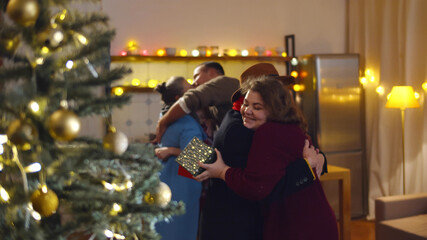 Excited family greeting grandparents with presents visiting on Christmas day
