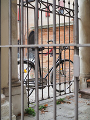 Fototapeta na wymiar Ferrara, Italy. Old town, Sant'Anna square. A bicycle seen through the railings.