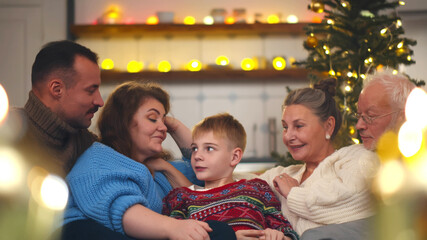 Happy large family resting on sofa together and talking on new year eve