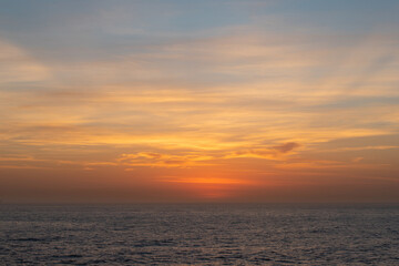 Naklejka na ściany i meble Orange and blue view of sunrise sky on the ocean.