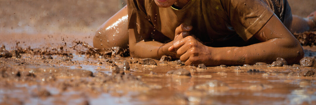 Mud race runners. Crawling, passing under a barbed wire obstacles during extreme obstacle race