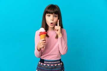 Little girl with a cornet ice cream isolated on blue background intending to realizes the solution...