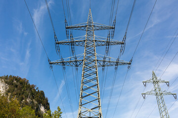 Overhead power line with blue sky and an upper bavarian mountain