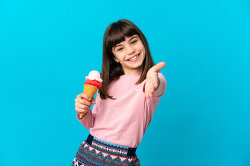 Little girl with a cornet ice cream isolated on blue background shaking hands for closing a good...
