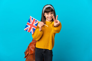 Little girl studying English isolated on blue background smiling and showing victory sign