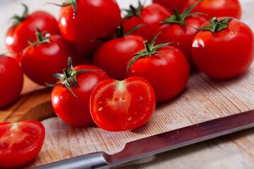 Closeup of whole and halved fresh organic tomatoes on wooden surface. Healthy vegetarian ingredient