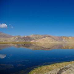 Spectacular view of pastel mountain reflection in high-altitude Bulunkul lake near the Pamir Highway in Gorno-Badakshan, Tajikistan