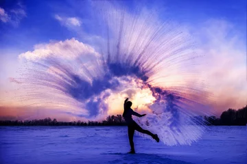 Cercles muraux Bleu foncé Silhouette of a sports girl at sunset in winter. Woman splashed boiling water on cold air.