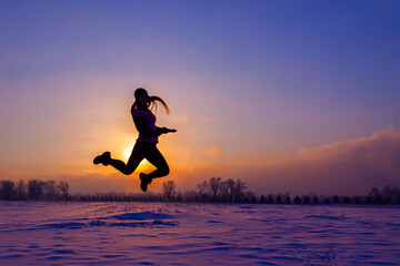 Girl on the bank of the winter sea at sunset. Woman splashes boiling water on cold air.