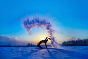 Silhouette of a sports girl at sunset in winter. Woman splashed boiling water on cold air.