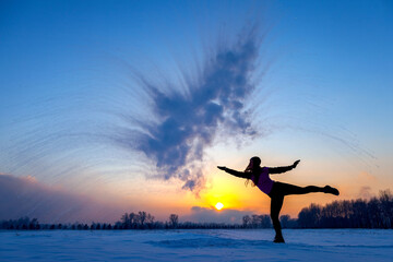 Fototapeta na wymiar Silhouette of a sports girl at sunset in winter. Woman splashed boiling water on cold air.