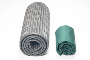 rolled up polyurethane mat and folded air mattress for camping and tourism isolated on white background