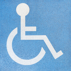 Rollstuhlfahrer - wei&szlig;es Zeichen auf einer blauen Betonplatte - Markierung am Boden f&uuml;r einen Behindertenparkplatz