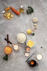 Ingredients for Making Cooking Arancini on a White Grey Marble Background. Cheese, Rice, Milk, Egg, Carrot, Parsley, Butter, Garlic, Bread Crumb, and Parmesan