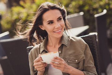 Photo portrait of attractive woman holding cup of coffee in two hands in windy weather with hair...