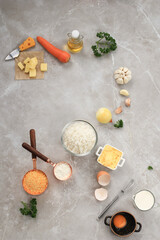 Ingredients for Making Cooking Arancini on a White Grey Marble Background. Cheese, Rice, Milk, Egg, Carrot, Parsley, Butter, Garlic, Bread Crumb, and Parmesan
