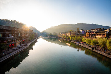 the river, the boat, stone bridge and the old houses at ancient phoenix town in the morning at...