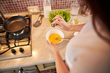 Woman is spicing the omelet with salt