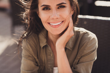 Photo portrait of beautiful woman touching face cheek with hand sitting in restaurant outdoors