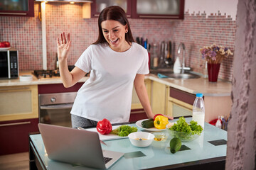 Excited woman waving hello to a laptop screen