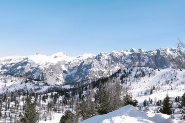 Top view from the ski slope to the snow-covered forest, mountains and the river covered with ice.