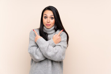 Obraz premium Young Colombian girl over isolated background pointing to the laterals having doubts