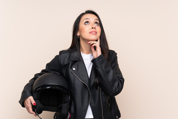 Young Colombian girl holding a motorcycle helmet over isolated background thinking an idea