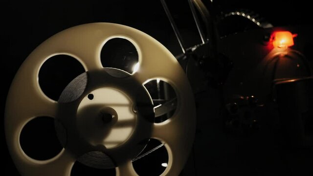 Close-up of a reel with a film rotating and light rays. Old 8mm film projector working in the dark room