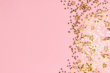 Gold stars confetti on a pink pastel background. Shiny concept with copy space.
