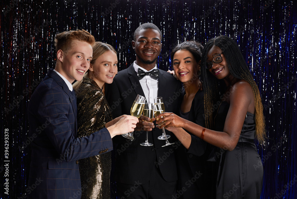 Wall mural waist up portrait of multi-ethnic group of friends clinking champagne glasses and smiling at camera 